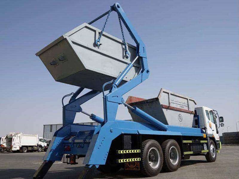 Skip loader with twin hydraulic arms lifting an open skip container Skip loader with twin hydraulic arms lifting an open skip container